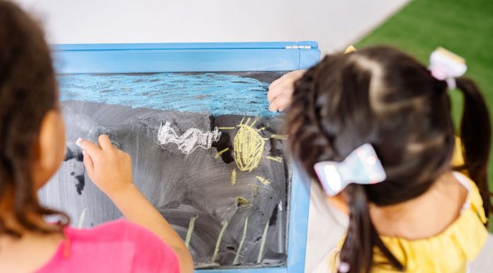 Children enjoying drawing on a blackboard in a vibrant classroom setting, highlighting creativity and education.