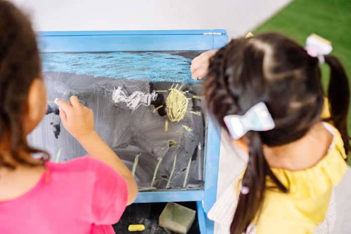 mejores-jardines-infancia-bayonne-guia-2026 Children enjoying drawing on a blackboard in a vibrant classroom setting, highlighting creativity and education.