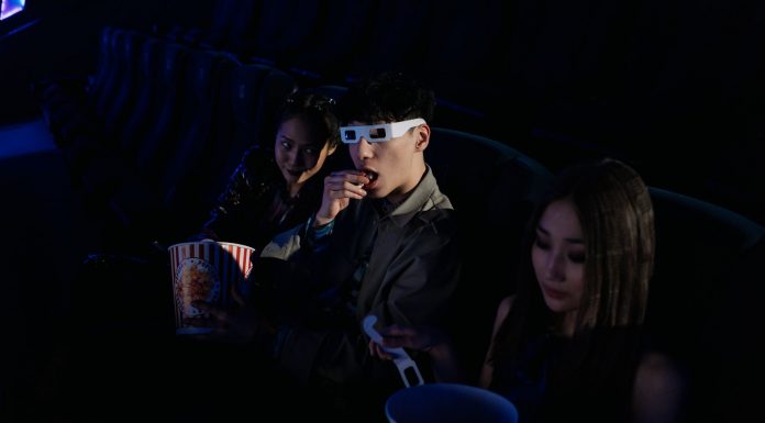 A group of young adults enjoying a movie at the cinema, complete with popcorn and 3D glasses.