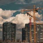 Construction site in Istanbul with cranes and buildings under a dramatic cloudy sky.