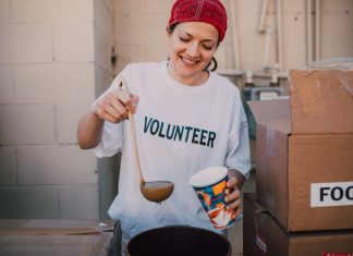 A cheerful volunteer serving food at a donation center, symbolizing generosity and community support.