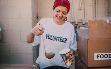 A cheerful volunteer serving food at a donation center, symbolizing generosity and community support.