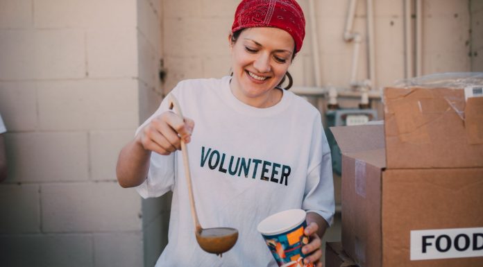 A cheerful volunteer serving food at a donation center, symbolizing generosity and community support.