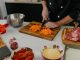Chef chops carrots on a cutting board surrounded by fresh ingredients in a modern kitchen.