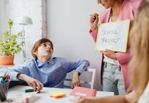 Parents Petition Board of Education to Delay Superintendent Contract Vote A teacher guiding teenagers through a school project in a modern classroom setting.
