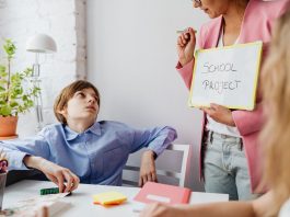Parents Petition Board of Education to Delay Superintendent Contract Vote A teacher guiding teenagers through a school project in a modern classroom setting.