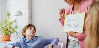 Parents Petition Board of Education to Delay Superintendent Contract Vote A teacher guiding teenagers through a school project in a modern classroom setting.