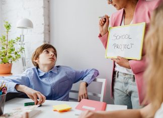 A teacher guiding teenagers through a school project in a modern classroom setting.