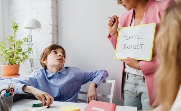 A teacher guiding teenagers through a school project in a modern classroom setting.