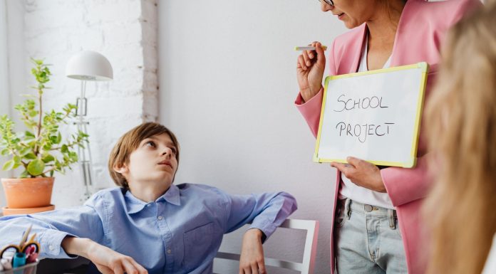 Parents Petition Board of Education to Delay Superintendent Contract Vote A teacher guiding teenagers through a school project in a modern classroom setting.