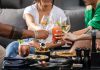 A group of friends enjoying cocktails and snacks at an outdoor gathering, clinking glasses in a cheerful toast.