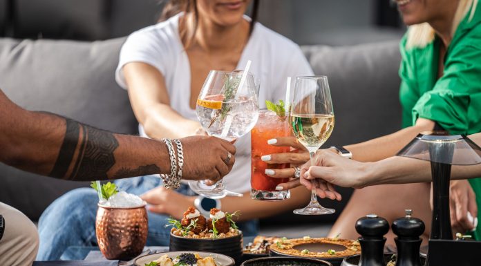 A group of friends enjoying cocktails and snacks at an outdoor gathering, clinking glasses in a cheerful toast.