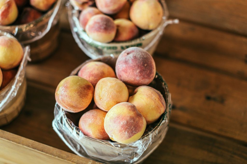 A collection of fresh peaches stacked in baskets, highlighting their juicy appeal and rustic setup.