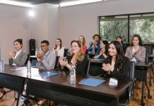 School Board Extends Superintendent’s Contract Five Years Amid Fierce Opposition A diverse group of adults applauding in a business seminar setting.