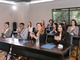 A diverse group of adults applauding in a business seminar setting.