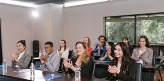 A diverse group of adults applauding in a business seminar setting.