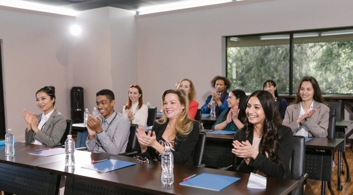 A diverse group of adults applauding in a business seminar setting.