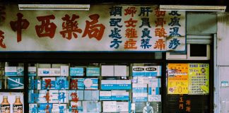 A traditional storefront with Asian script and various posters displayed in the window.
