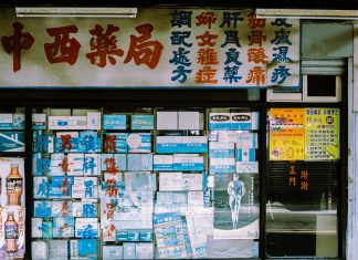 A traditional storefront with Asian script and various posters displayed in the window.