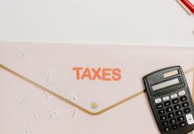 Flat lay of a calculator and folder labeled 'Taxes' for finance and accounting.
