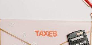 Flat lay of a calculator and folder labeled 'Taxes' for finance and accounting.