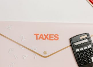 Flat lay of a calculator and folder labeled 'Taxes' for finance and accounting.