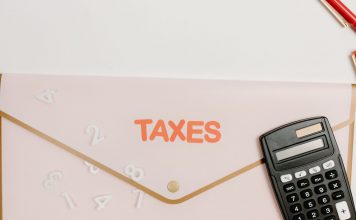 Flat lay of a calculator and folder labeled 'Taxes' for finance and accounting.