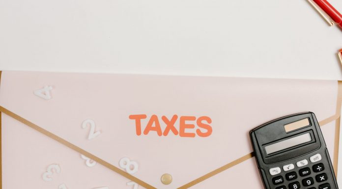 Flat lay of a calculator and folder labeled 'Taxes' for finance and accounting.