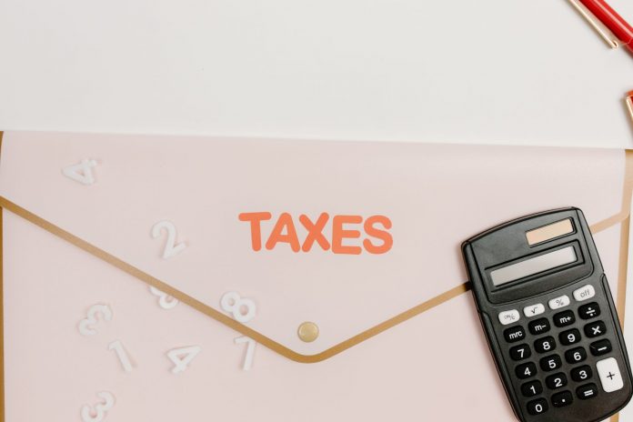 solomon-unveils-886-5m-jersey-city-budget-with-15- Flat lay of a calculator and folder labeled 'Taxes' for finance and accounting.