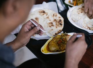Crop anonymous person eating tasty meat with vegetables and pita for dinner in cafe
