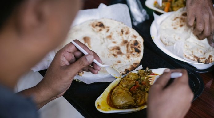 Crop anonymous person eating tasty meat with vegetables and pita for dinner in cafe