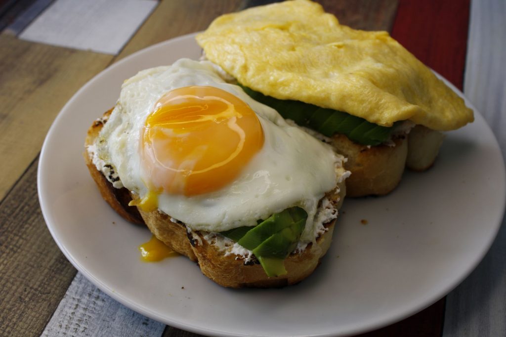 Tasty breakfast with fried egg and avocado on toast, ideal for food lovers.