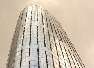 Two Climbers Scale Empire State Building With Peace Banner, Proposal and Arrest Follow Glass skyscraper with window cleaners scaling the facade against a cloudy sky.