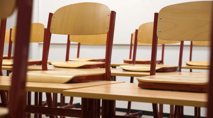 A modern and empty classroom featuring wooden chairs and desks with a focus on education and learning spaces.