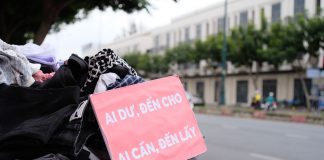 Clothes donation on city street with sign offering free items to those in need.
