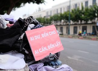 Clothes donation on city street with sign offering free items to those in need.