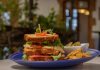 Where to grab lunch in Jersey City this week Mouthwatering club sandwich with crispy fries on a blue plate, perfect for a hearty meal.