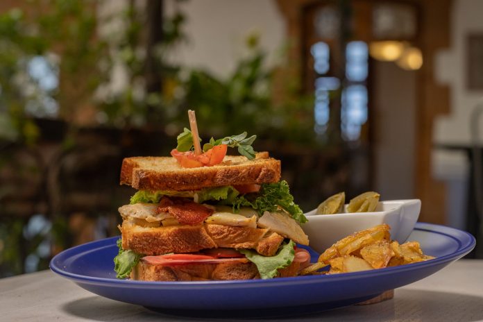 where-to-grab-lunch-in-jersey-city-this-week Mouthwatering club sandwich with crispy fries on a blue plate, perfect for a hearty meal.