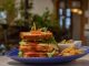 Where to grab lunch in Jersey City this week Mouthwatering club sandwich with crispy fries on a blue plate, perfect for a hearty meal.