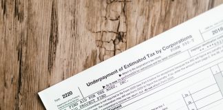 Who really pays for Jersey City’s tax abatements? Close-up of a corporate tax form on a textured wooden surface, highlighting document details.