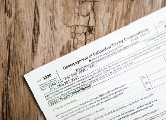 Who really pays for Jersey City’s tax abatements? Close-up of a corporate tax form on a textured wooden surface, highlighting document details.