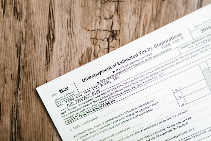 who-really-pays-for-jersey-city-s-tax-abatements- Close-up of a corporate tax form on a textured wooden surface, highlighting document details.