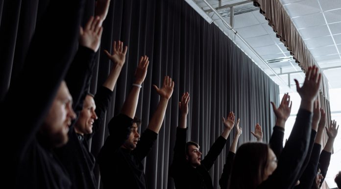 A dynamic group performance with raised arms and synchronized movements indoors.