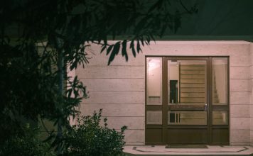 Your Guide to Funeral Homes in Jersey City A serene nighttime view of a modern building entrance with surrounding foliage, creating a warm and inviting atmosphere.