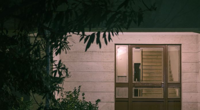 Your Guide to Funeral Homes in Jersey City A serene nighttime view of a modern building entrance with surrounding foliage, creating a warm and inviting atmosphere.