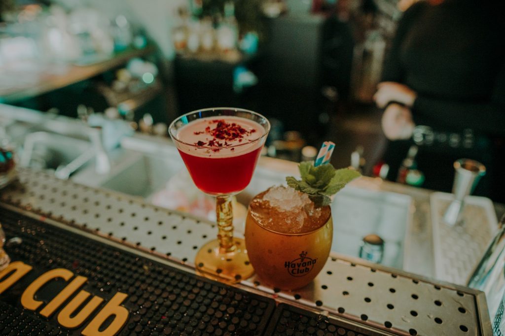 Two vibrant cocktails on a bar counter showcasing a sophisticated nightlife atmosphere.