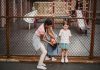 Children having fun at a playground, playing around a fence, enjoying summer day.