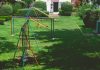 Vibrant outdoor playground with swings and slides in a lush green park setting under a bright sky.