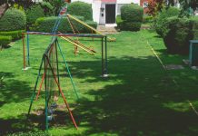 Vibrant outdoor playground with swings and slides in a lush green park setting under a bright sky.