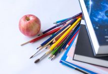 Colorful school supplies arranged with an apple on a white surface, ideal for education themes.